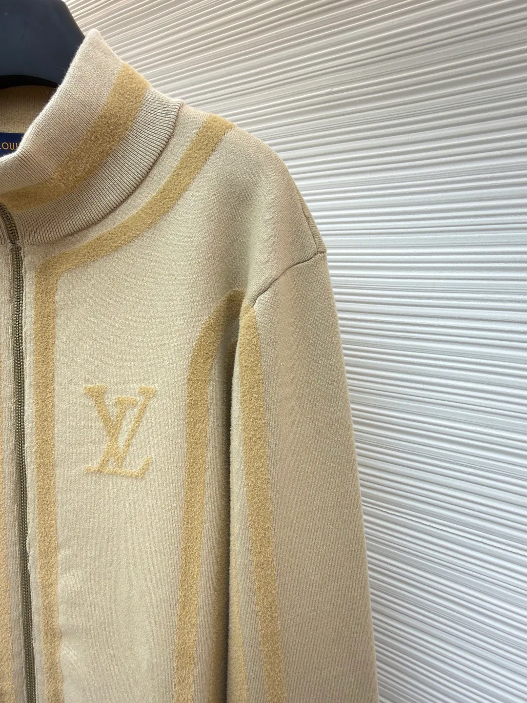 LOUIS VUITTON two-color splicing intarsia zipper jacket ●Original version: purchased and developed at 20700 ●Item number: 1681968-C15 ●Fabric: nylon fabric ●Technology: intarsia production ●Color: khaki ●Version: fitted version ●Weight: about 1020 grams ●Size: XS-S-M-L ●Description: Made of 43% nylon, 32% cotton and 25% viscose blended fabric, which has both comfort and stiffness. The designer used two-tone intarsia technology to allow contrasting color strips to run through the sleeves and body, forming a smooth visual extension. Different areas create subtle three-dimensional texture effects by changing knitting density and stitching methods. The chest is decorated with a delicate intarsia LV logo, and the Vuitton word is presented in elegant font on the back, showing brand recognition in every detail. The collar, cuffs and hem made of rib knitting technology not only enhance the stability of the silhouette, but also echo the overall design language. The front placket features a smooth zipper closure and practical slip pockets on both sides for added functionality. The entire piece perfectly interprets the exquisite aesthetics of sports and leisure style through the ingenious combination of fabric texture and craftsmanship details. The overall wiring is straight and delicate, the fabric is comfortable and soft, and the color is consistent without color difference. It can be matched with the same style to create a fashionable look and control various occasions. Customized accessories, complete with three standards, same style for men and women!